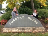 Two women stood behind the Dorothy House stone sign