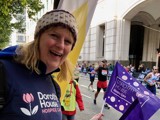 Volunteer in Dorothy House jumper waving flag to support runners