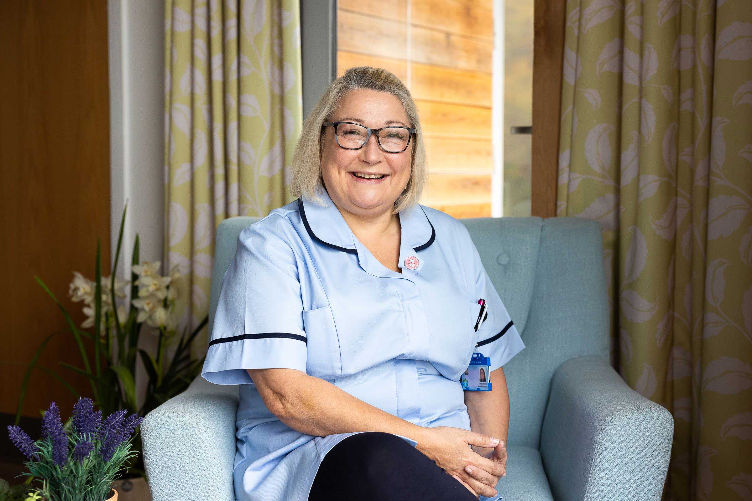Carer sitting in chair smiling at camera