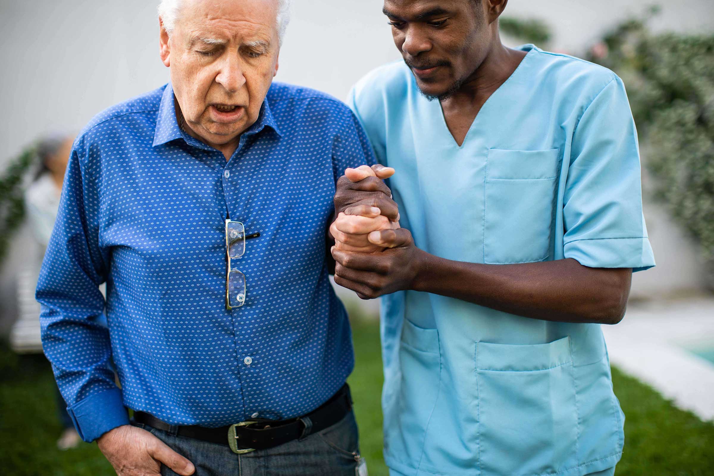 Male nurse helping old man walk