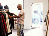 Young Black Man Browsing Through Clothes On A Rail